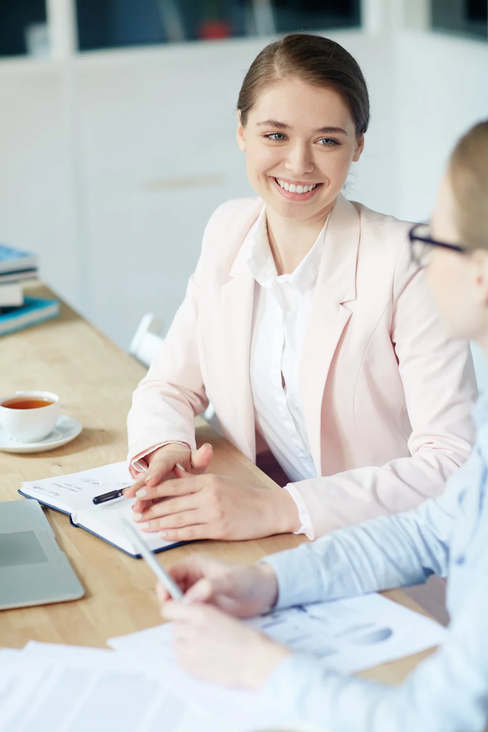 Asesoría laboral personalizada en RM Consulting – Atención profesional en oficina Dos mujeres en oficina conversan mientras revisan documentos, una sonríe con actitud profesional, representando una asesoría laboral. Foto de pressfoto de freepik.